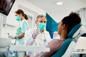 Dentist and assistant helping a patient with their dental emergency 