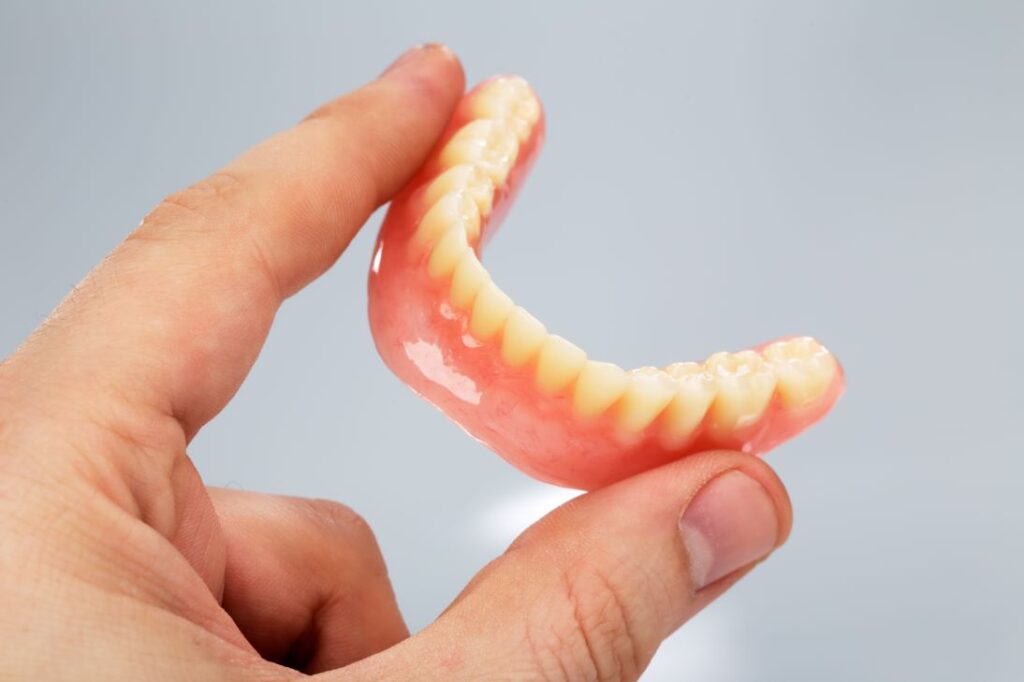 A man’s hand holding a bottom denture